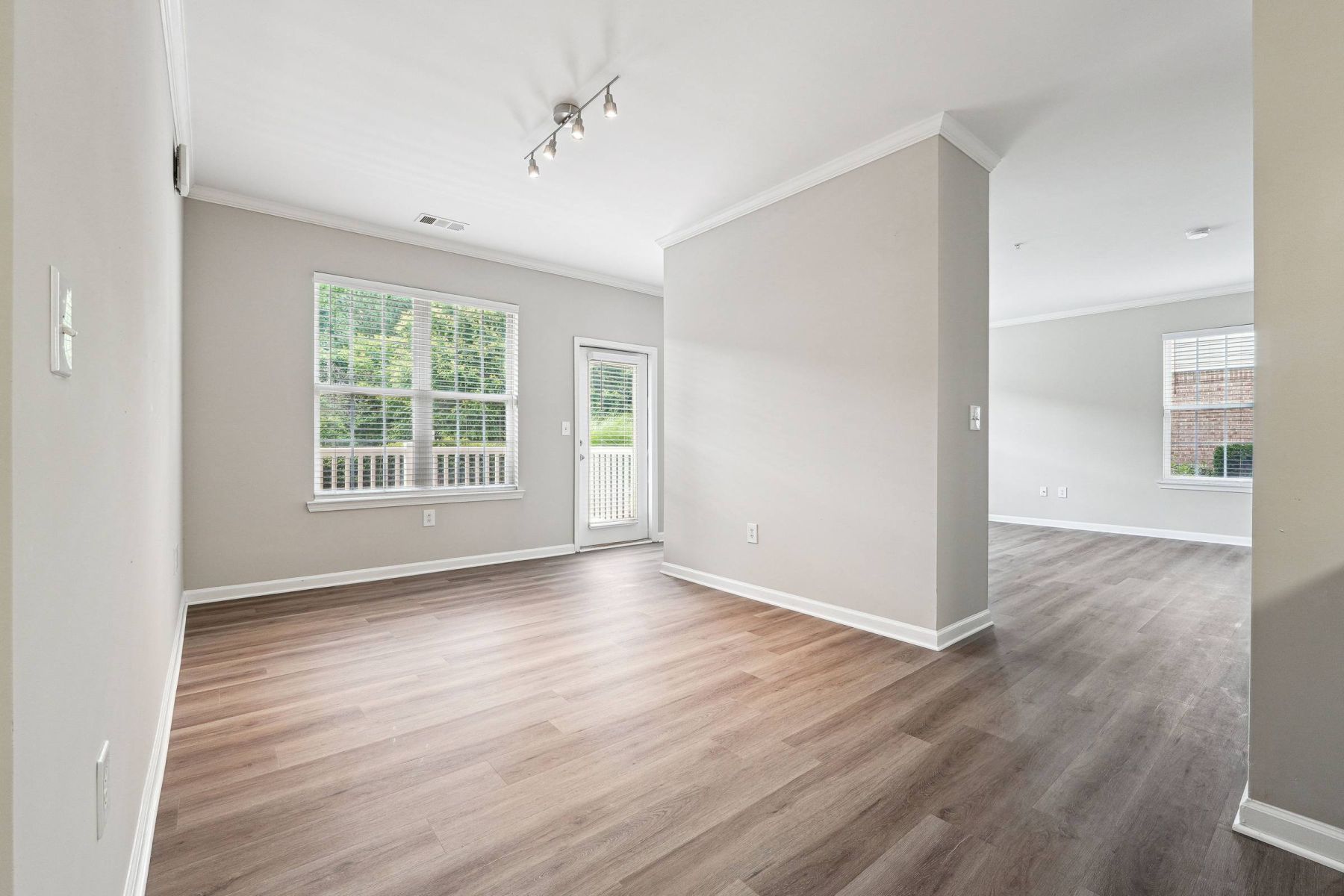 Empty room with wood floors, ceiling fan, and sliding glass door leading to a patio with vertical blinds at Apex West Midown.